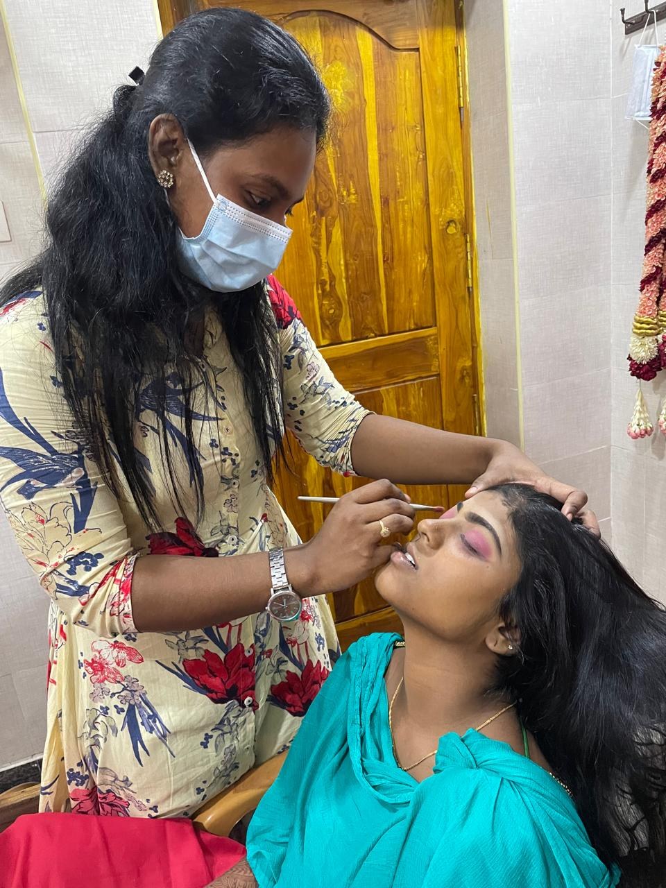 Kalaipriya R K applying eye makeup to a bride, close-up detail work