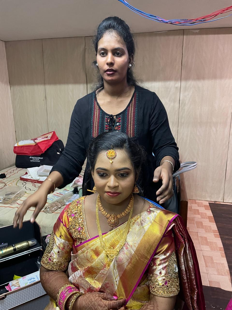 Kalaipriya R K with a bride, adding final touches to her bridal look