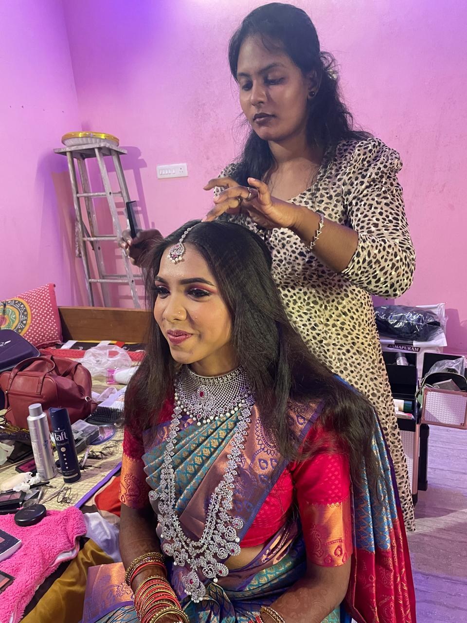 Kalaipriya R K styling hair for a bride in a red saree