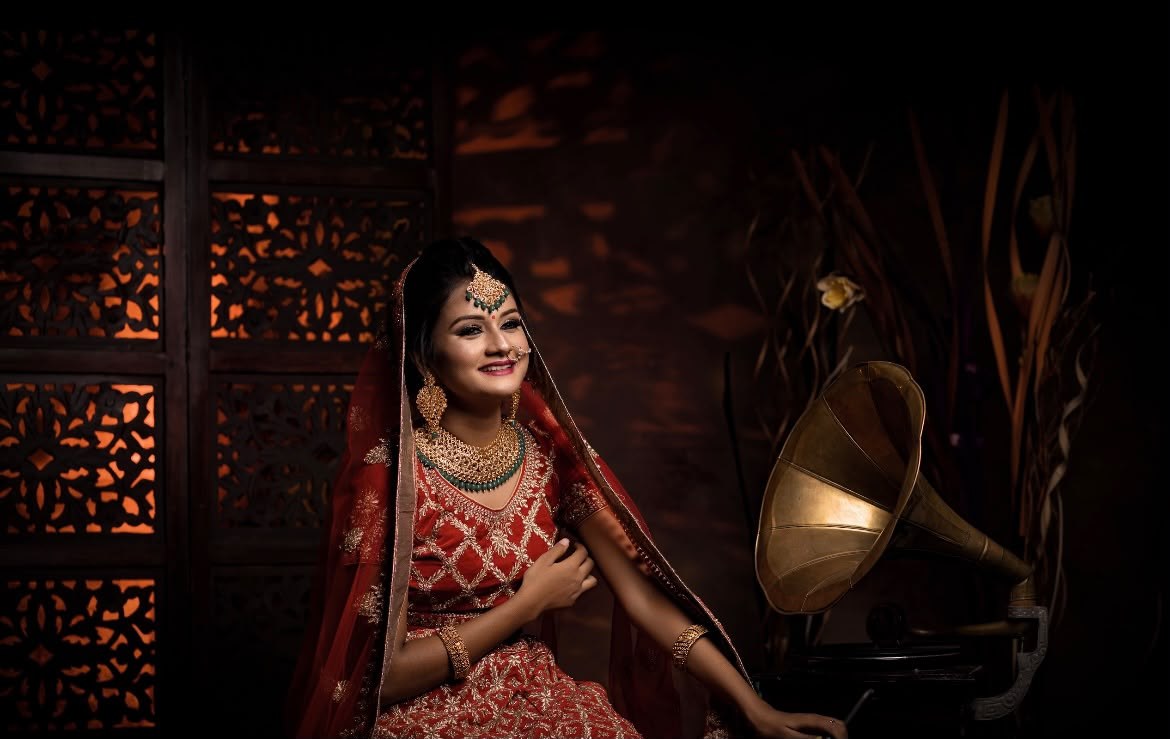 Bridal portrait in a richly detailed red lehenga against a moody backdrop