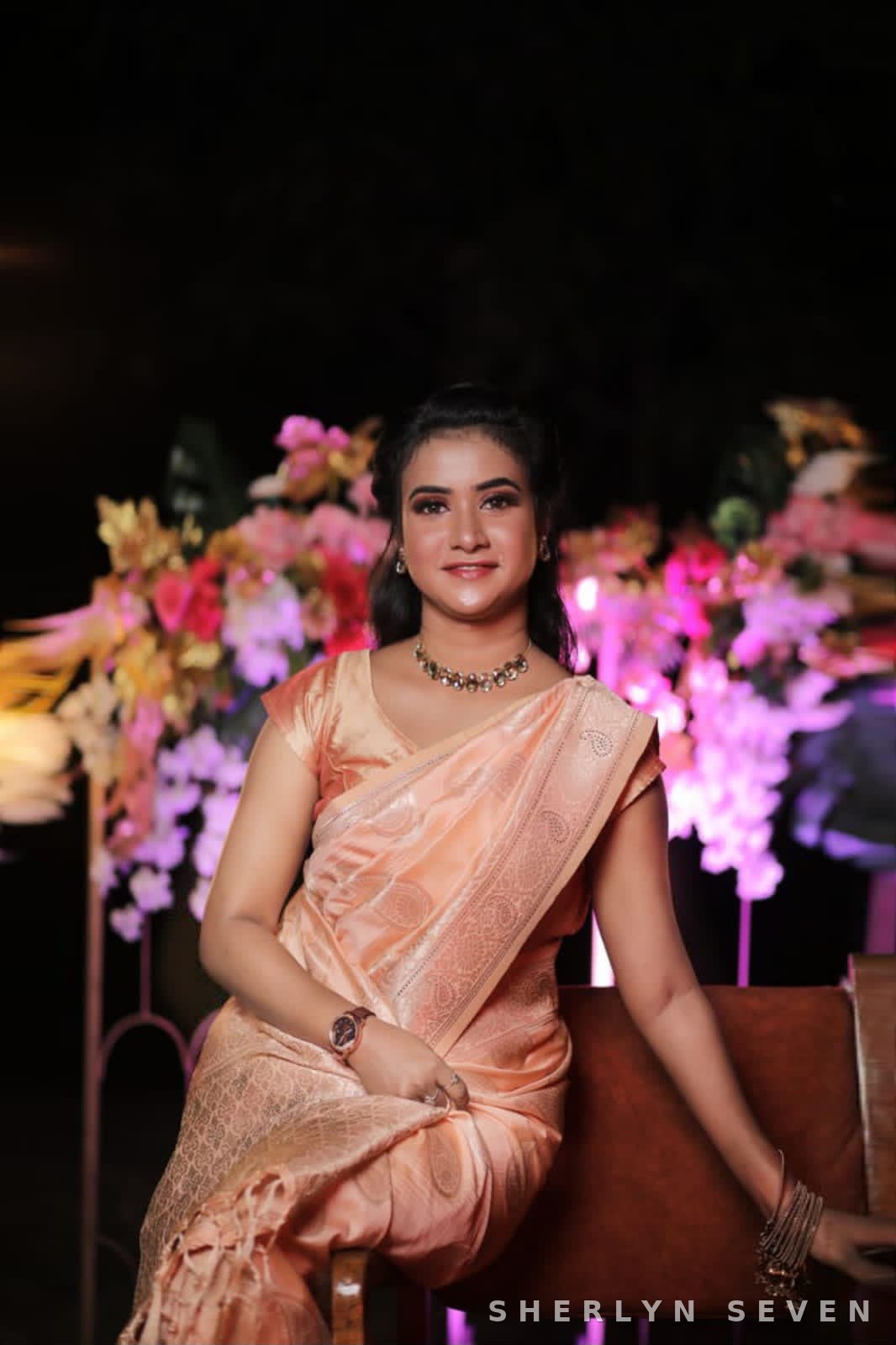 Reception look in a peach saree with floral backdrop