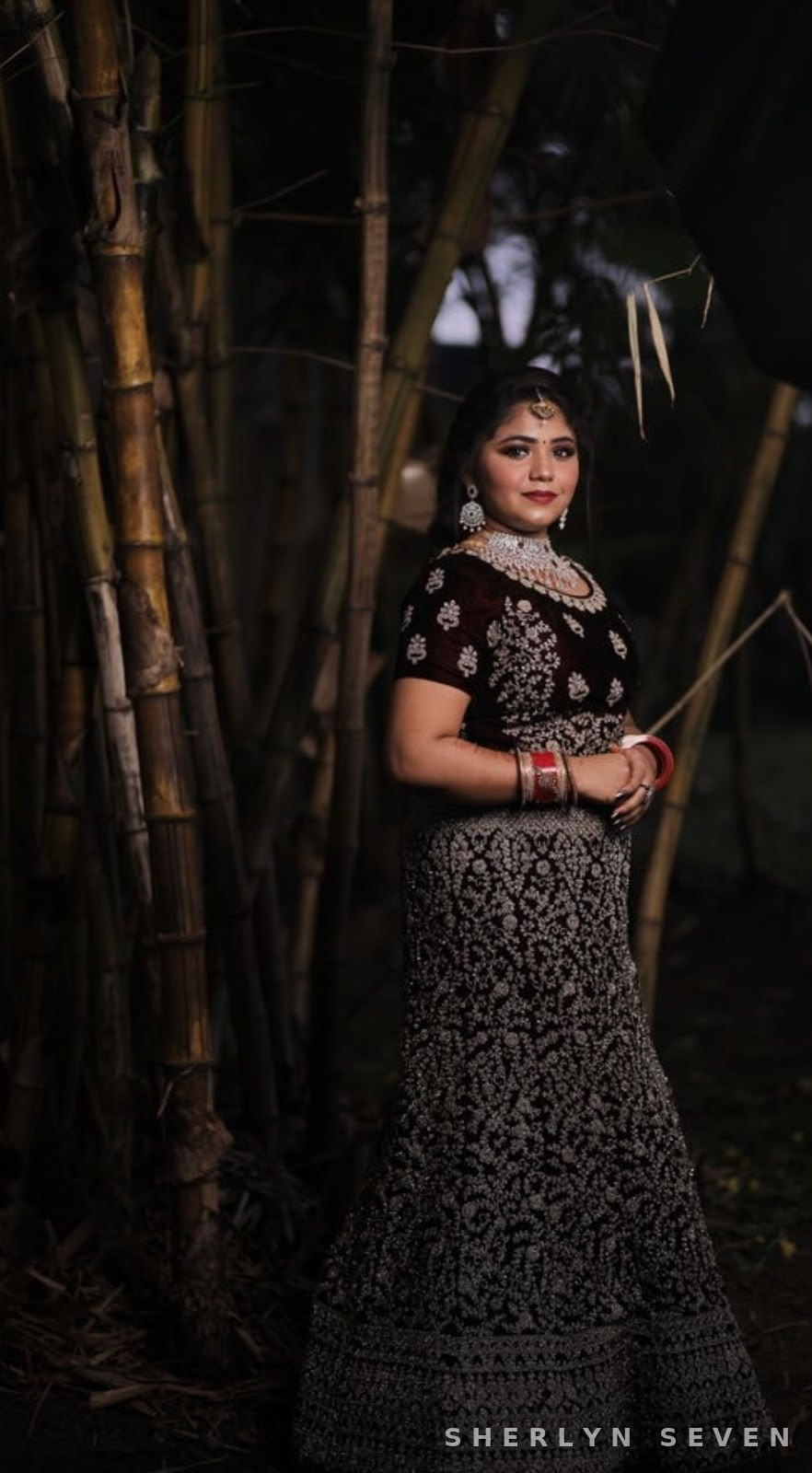 Editorial occasion look in a black lehenga against a bamboo backdrop