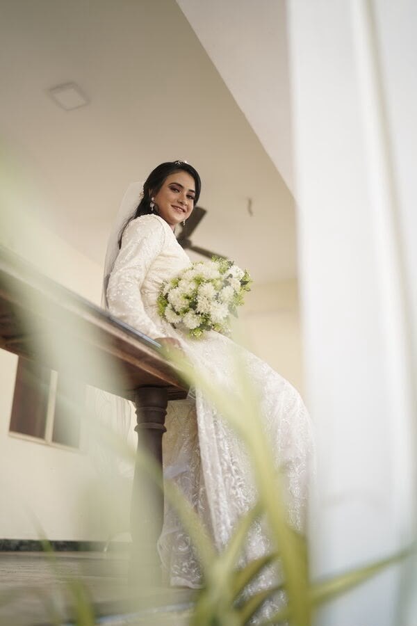 Bride in a veiled bridal look descending a staircase with a bouquet